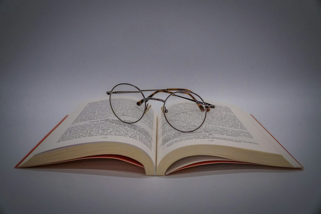 Open book with reading glasses resting on top