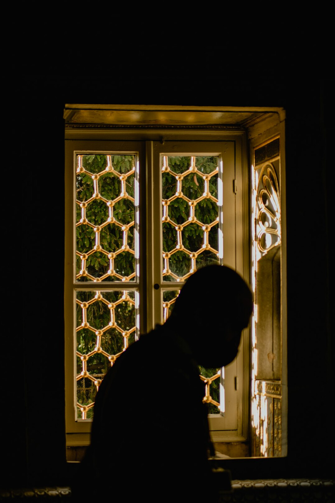 Person writing thoughtfully in a journal near a window